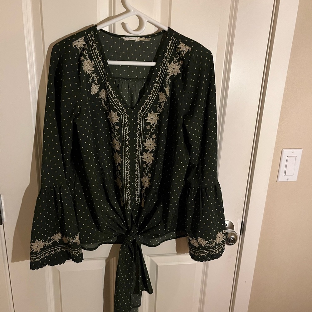Women’s olive green fall top with tan floral embroidery.